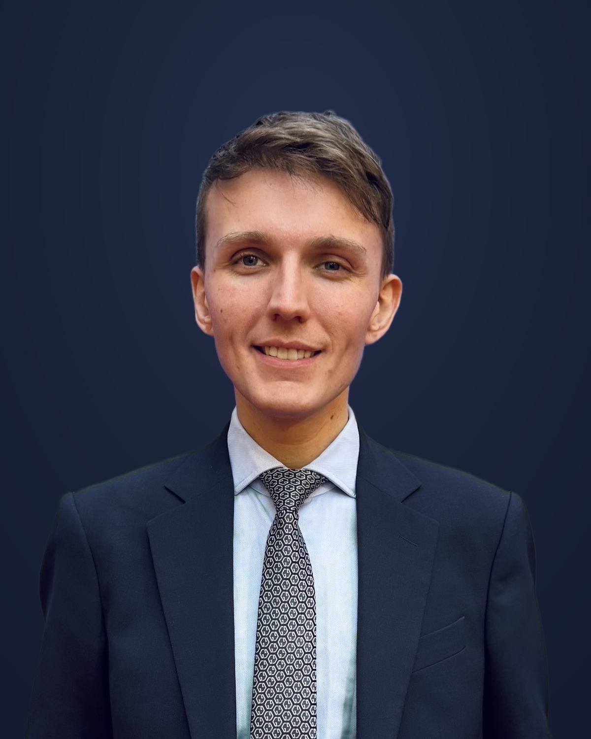 Portrait of Sebastian in a navy suit against a navy background